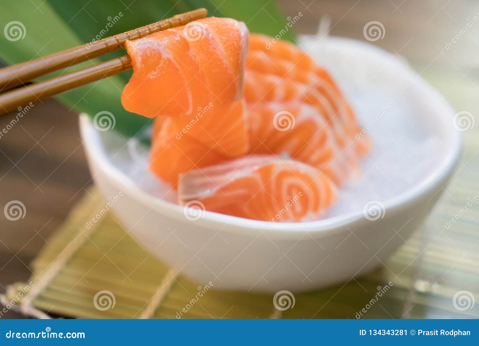 chopsticks with salmon sashimi with salmon sashimi on ice in with bowl. japanese food in asian restuarant