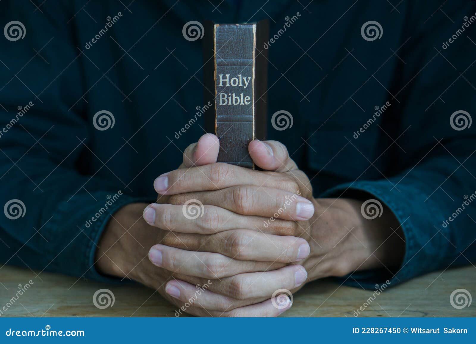 Christian Man Holding Bible Hands Folded In Prayer On A Holy Bible On