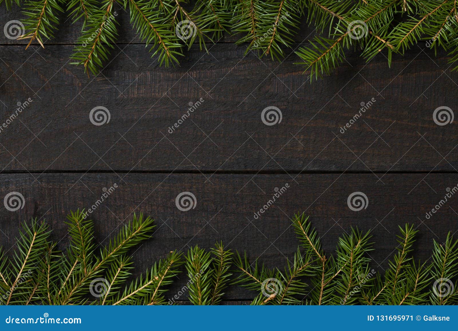 dark rustic wood table flatlay - christmas background with green fir tree branch frame. top view with free space for copy text
