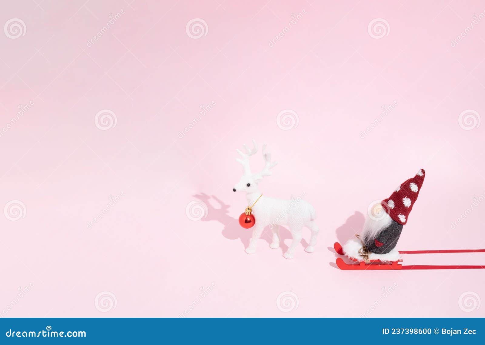 christmas composition on a pastel pink background. santa on a red sled and one white reindeer, red decoracion bauble. xmas and