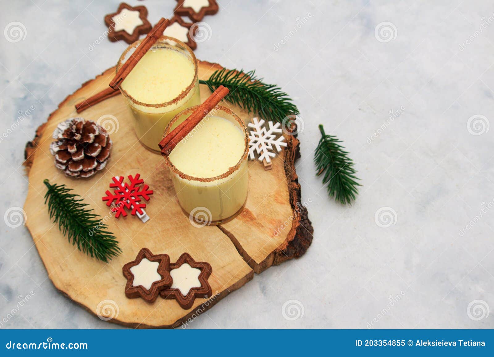 christmas drink egnog in two glasses with chocolate chip cookies and decor on wooden table on concrete background