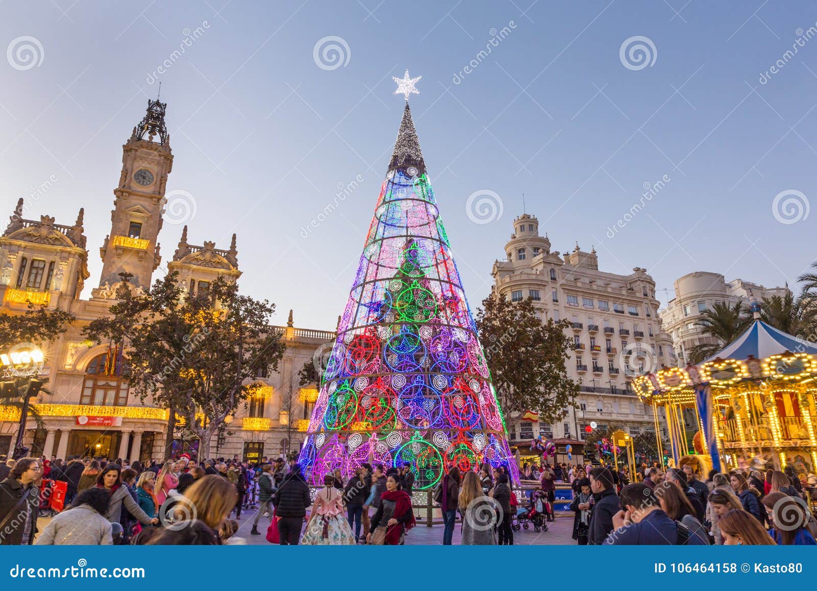 Christmas with Colorful Christmas Tree and Carousel on Modernisme Plaza of the City Hall of Valencia, Spain. Editorial Stock Photo - city, night: 106464158