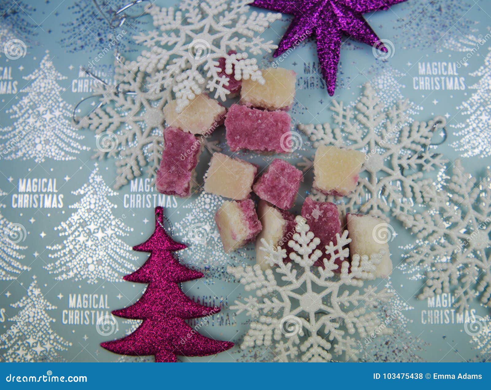 Christmas food photography picture of seasonal old fashioned English sweets of pink and white coconut ice on light blue shiny silver color background with