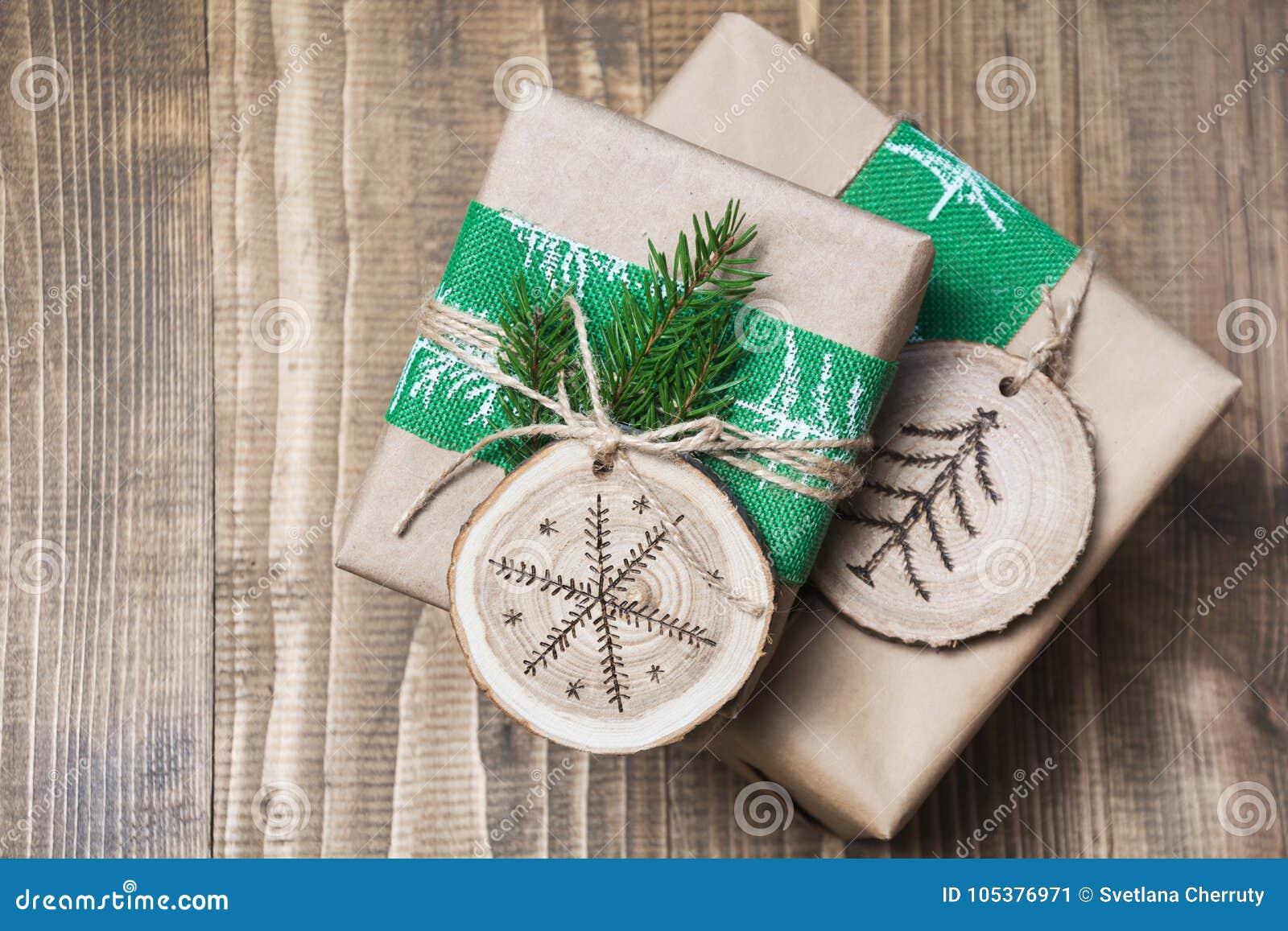 christmas gift box in rustic style wrapped in paper with decor of wooden sliced with woodburning .