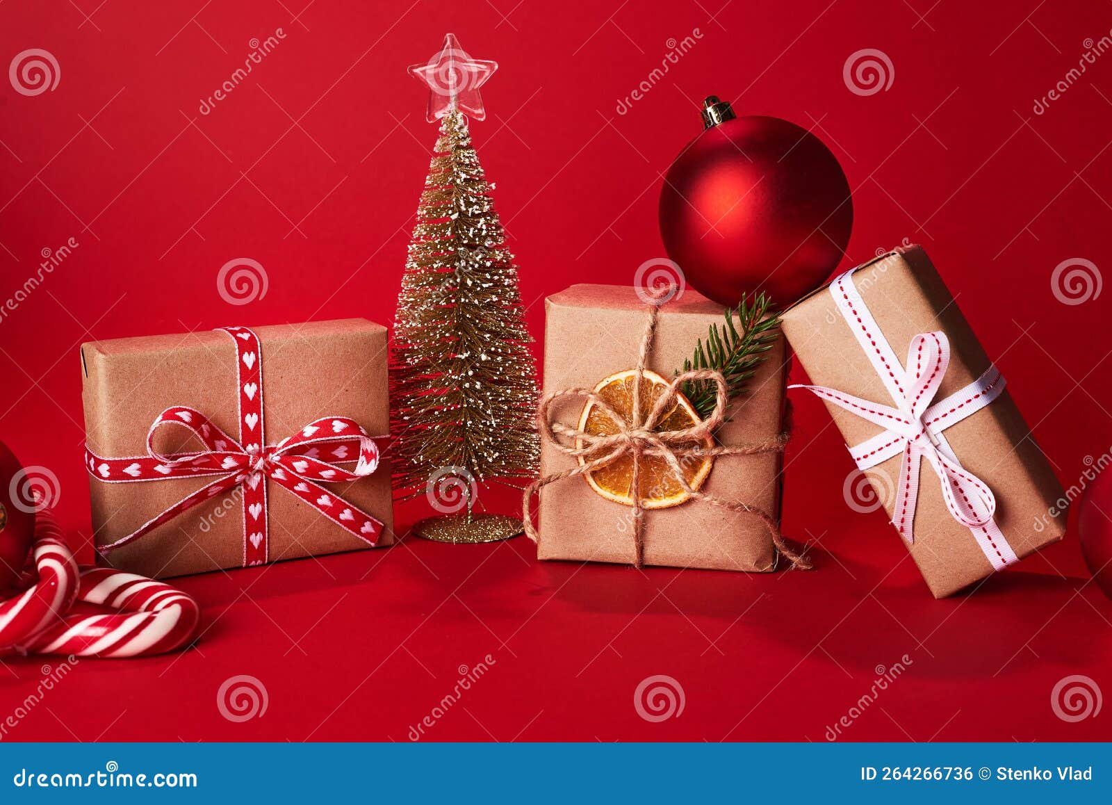 Christmas Gifts Near Small Christmas Tree on Red Background. Greeting