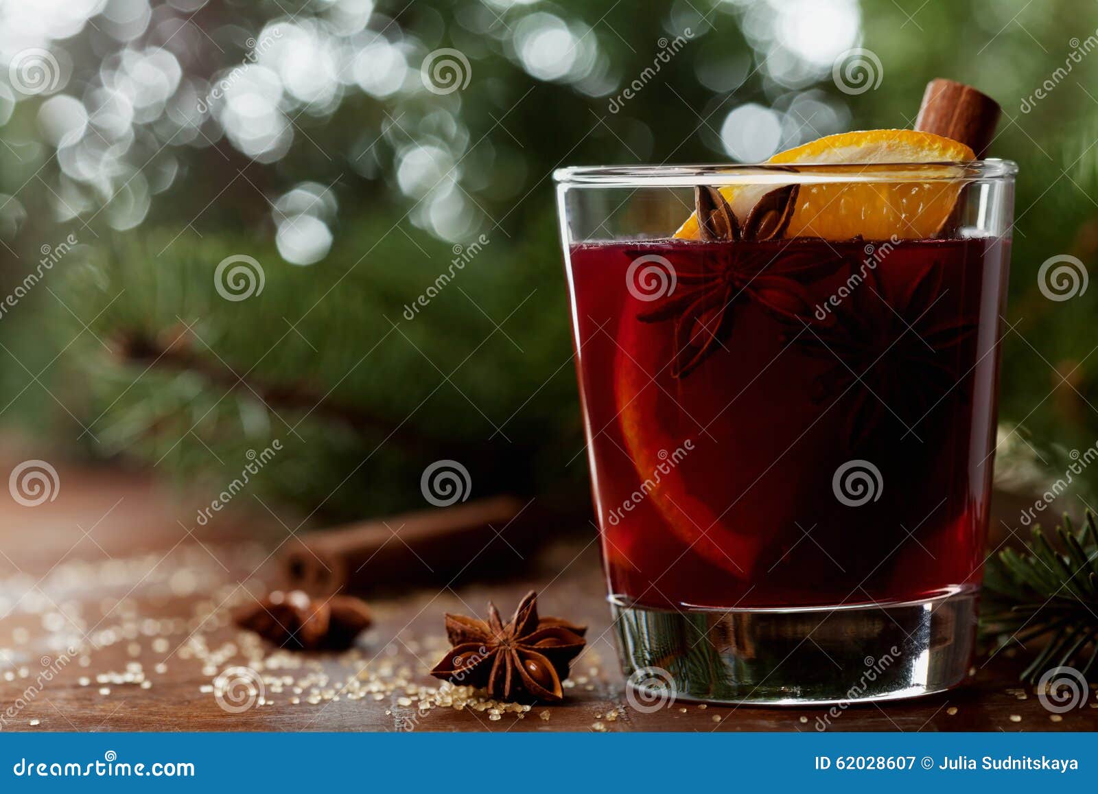 christmas mulled wine or gluhwein with spices and orange slices on rustic table, traditional drink on winter holiday, magic light
