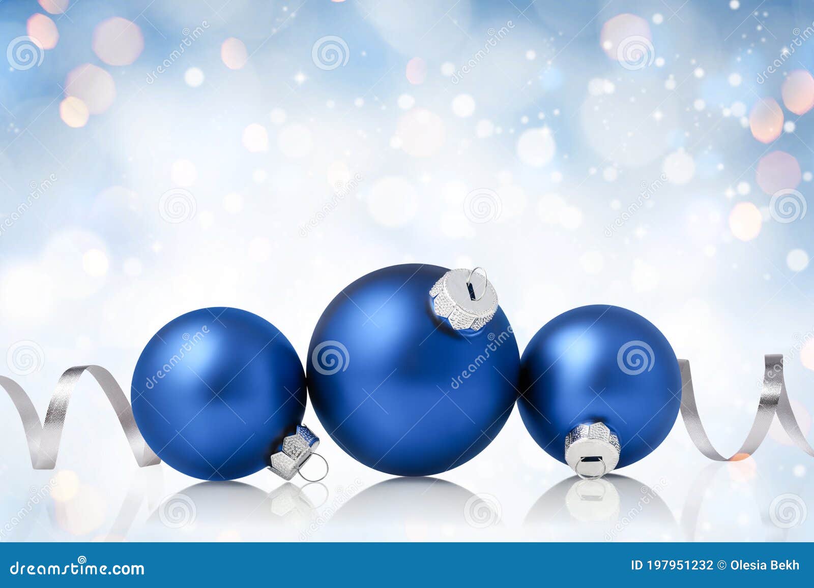 christmas and new year greeting card. holiday ornament, winter decoration. blue christmas baubles with silver ribbon over bokeh