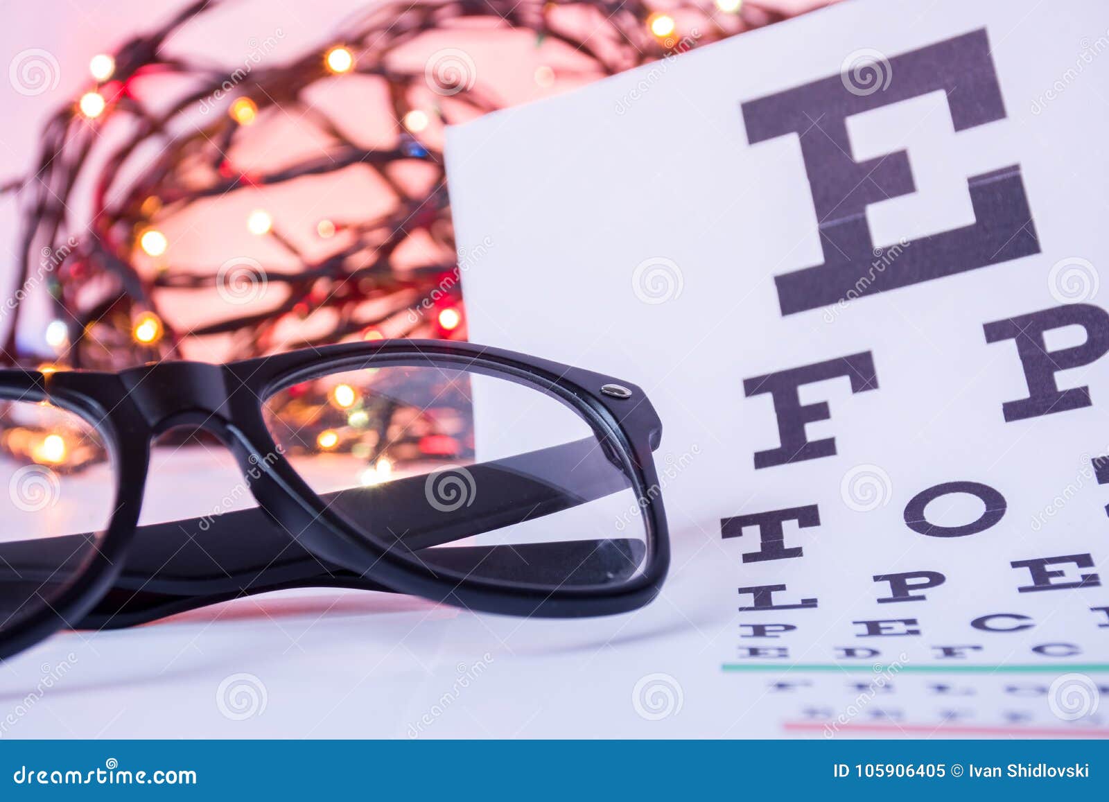 christmas and new year in ophthalmology optometry. eyeglasses and ophthalmological table for visual acuity test in foreground with