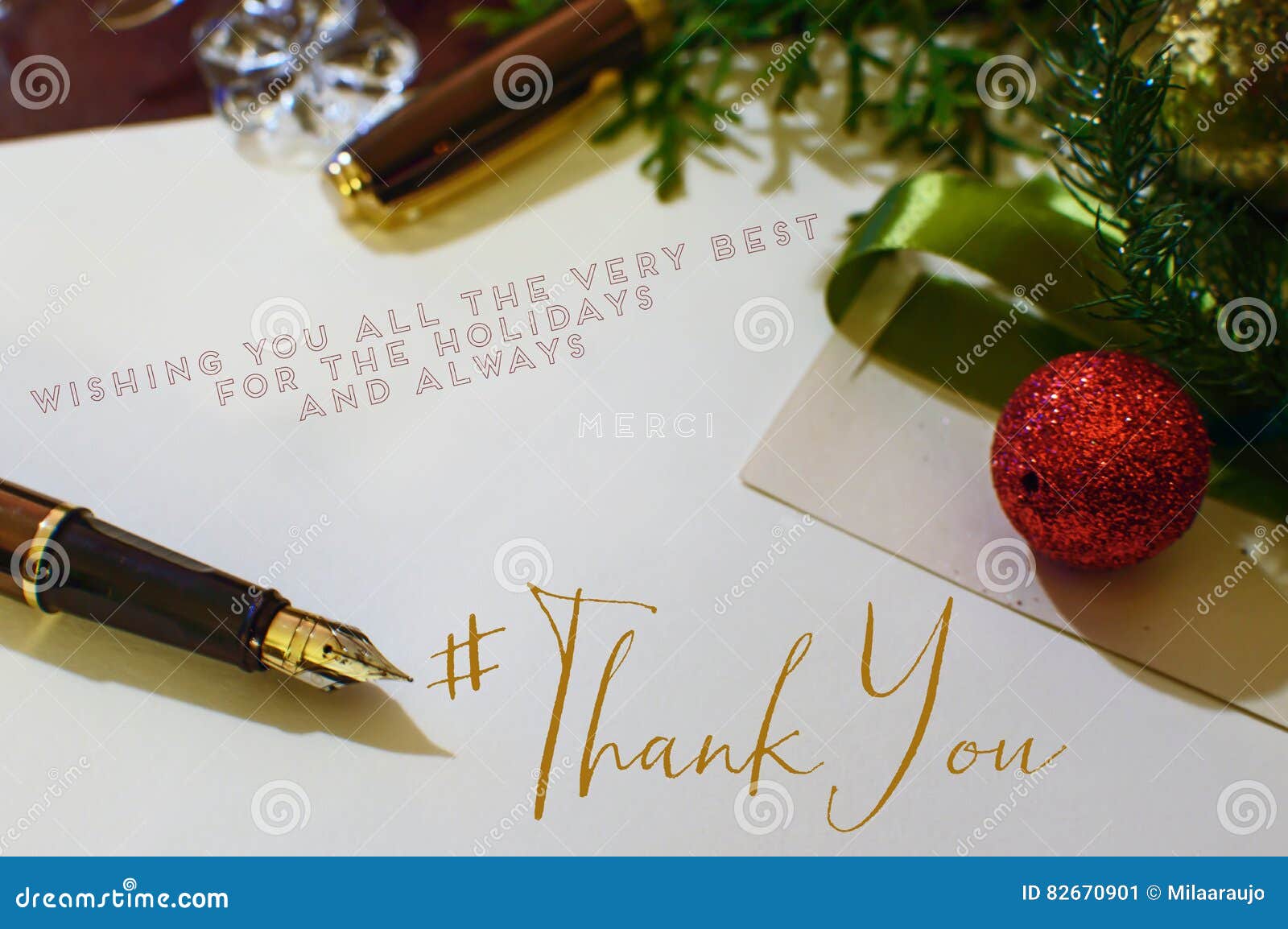 Gold Fountain pen on desk with christmas ornaments and evergreen tree gold and crystal writing thank you notes at the end of year for seasons greetings