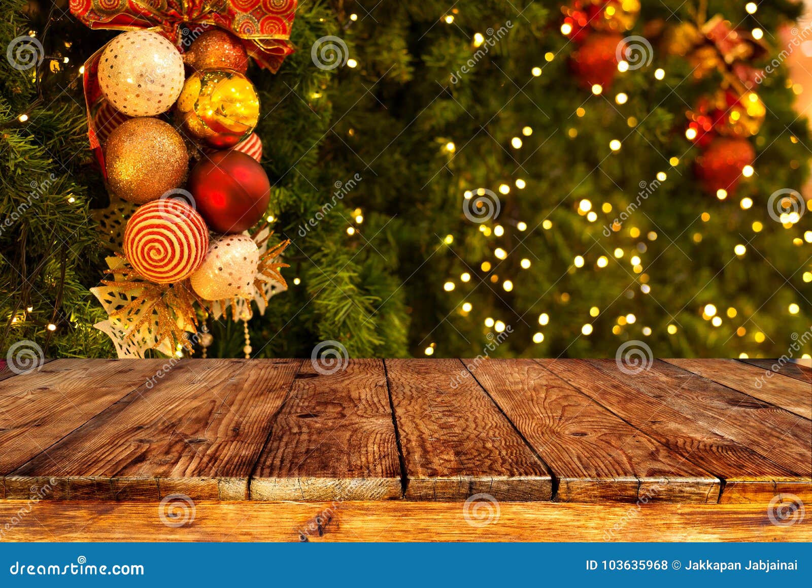 christmas tree background with decoration and blurred light bokeh with empty dark wooden deck table for product montage.