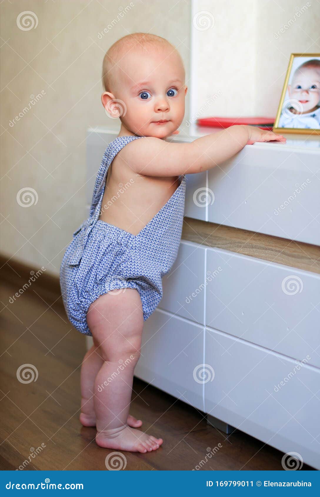 Chubby Baby Learning To Stand Up Holding On To The Furniture Stock