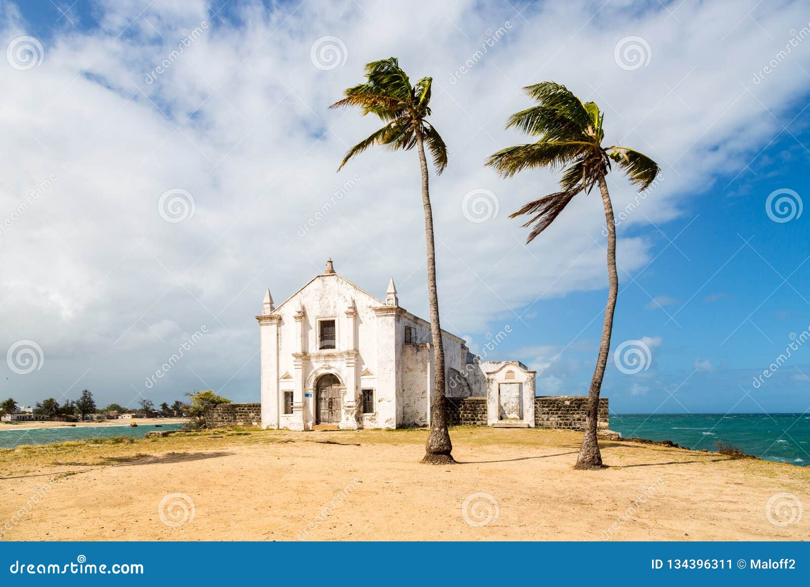church and fortress of san antonio on mozambique island, with two palm trees on sand. indian ocean coast, nampula province.