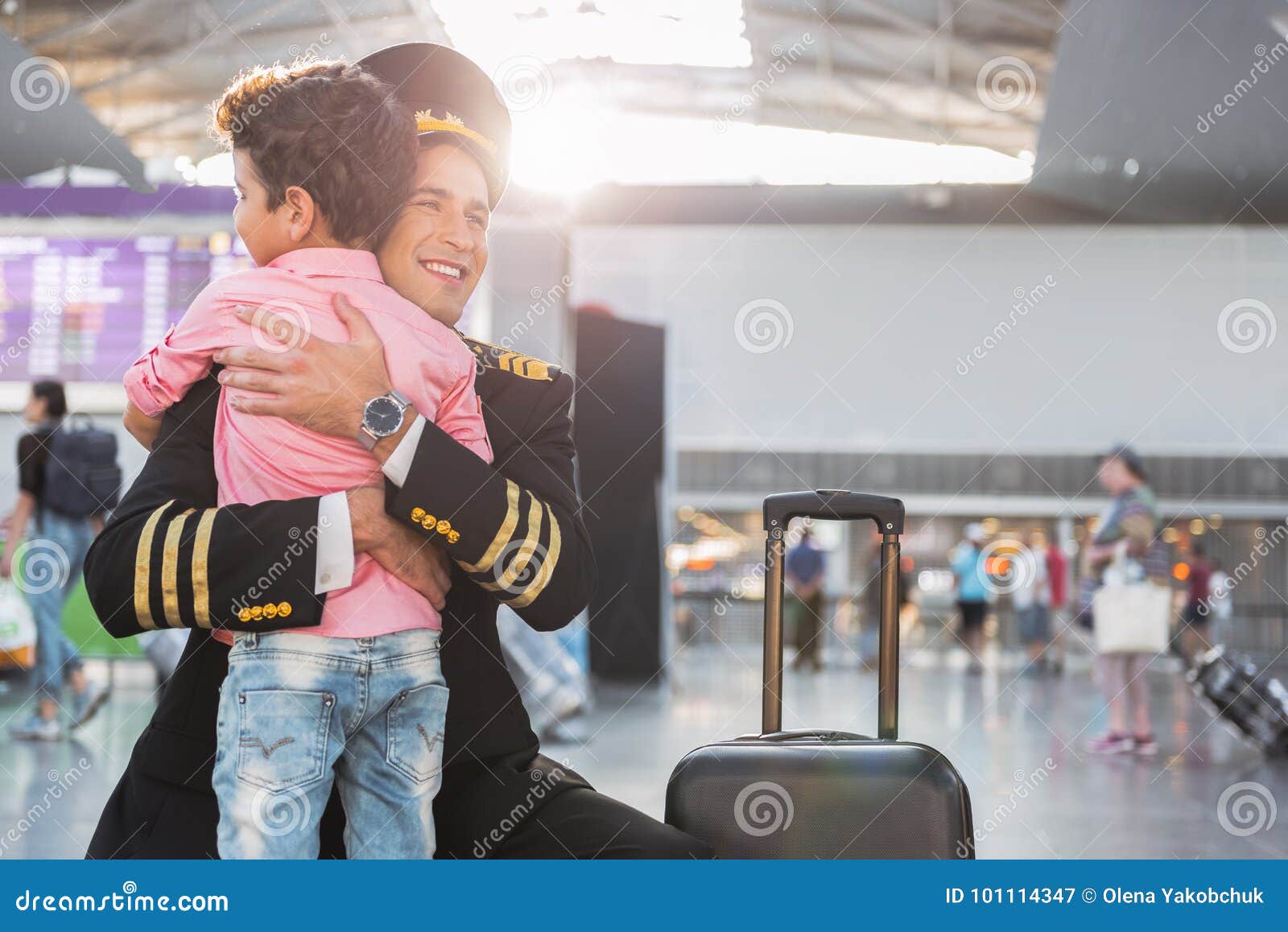 Chłopiec spotkania lotnik w lotnisku. Jestem w ten sposób szczęśliwy widzieć ciebie Pilot jest kucający jego syna i ściskający On patrzeje na boku z uśmiechem Odbitkowa przestrzeń na prawej stronie