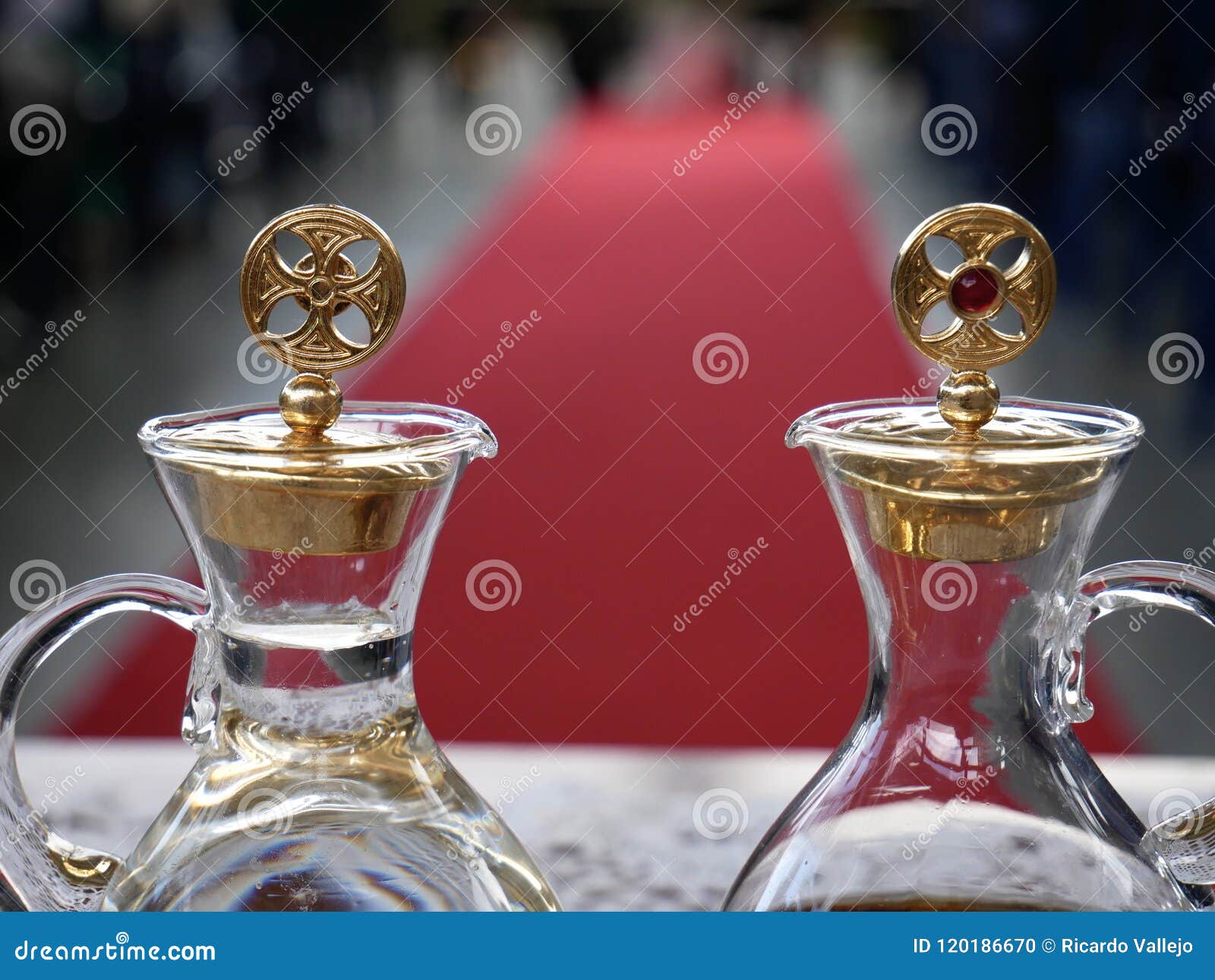Ciérrese Para Arriba De Vinagreras Con Agua Y El Vino Listos Para La Masa Católica Con La Alfombra Roja Y La Gente En El Fondo Foto de archivo - Imagen de cristal, Ciérrese Para Arriba De Vinagreras Con Agua Y El Vino Listos Para La Masa Católica Con La Alfombra Roja Y La Gente En El Fondo Foto de archivo - Imagen de cristal,