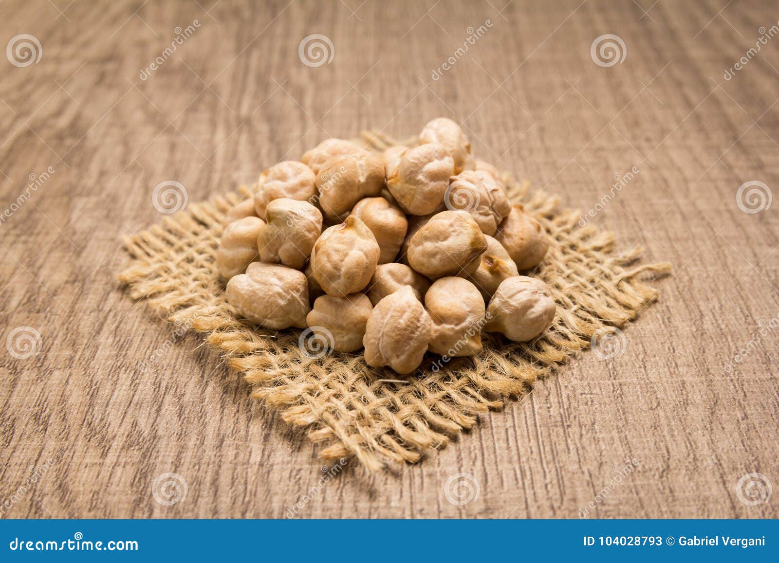 chickpeas legume. grains on square cutout of jute. wooden table.