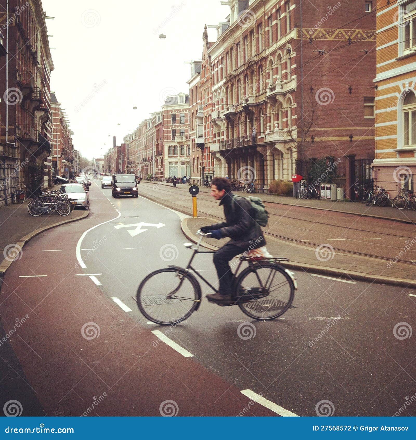 Ciclista em Amsterdão. Ciclista masculino que cruza uma rua em Amsterdão, Holland