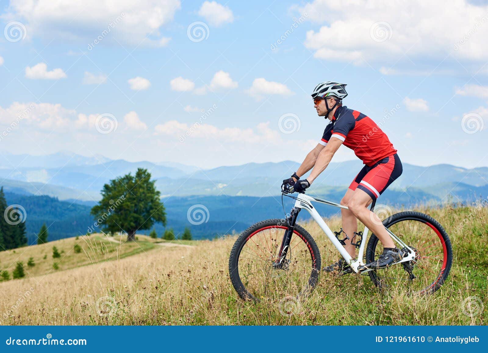 Ciclista de montaña europeo joven hermoso en ropa deportiva y equipo de  protección de pie