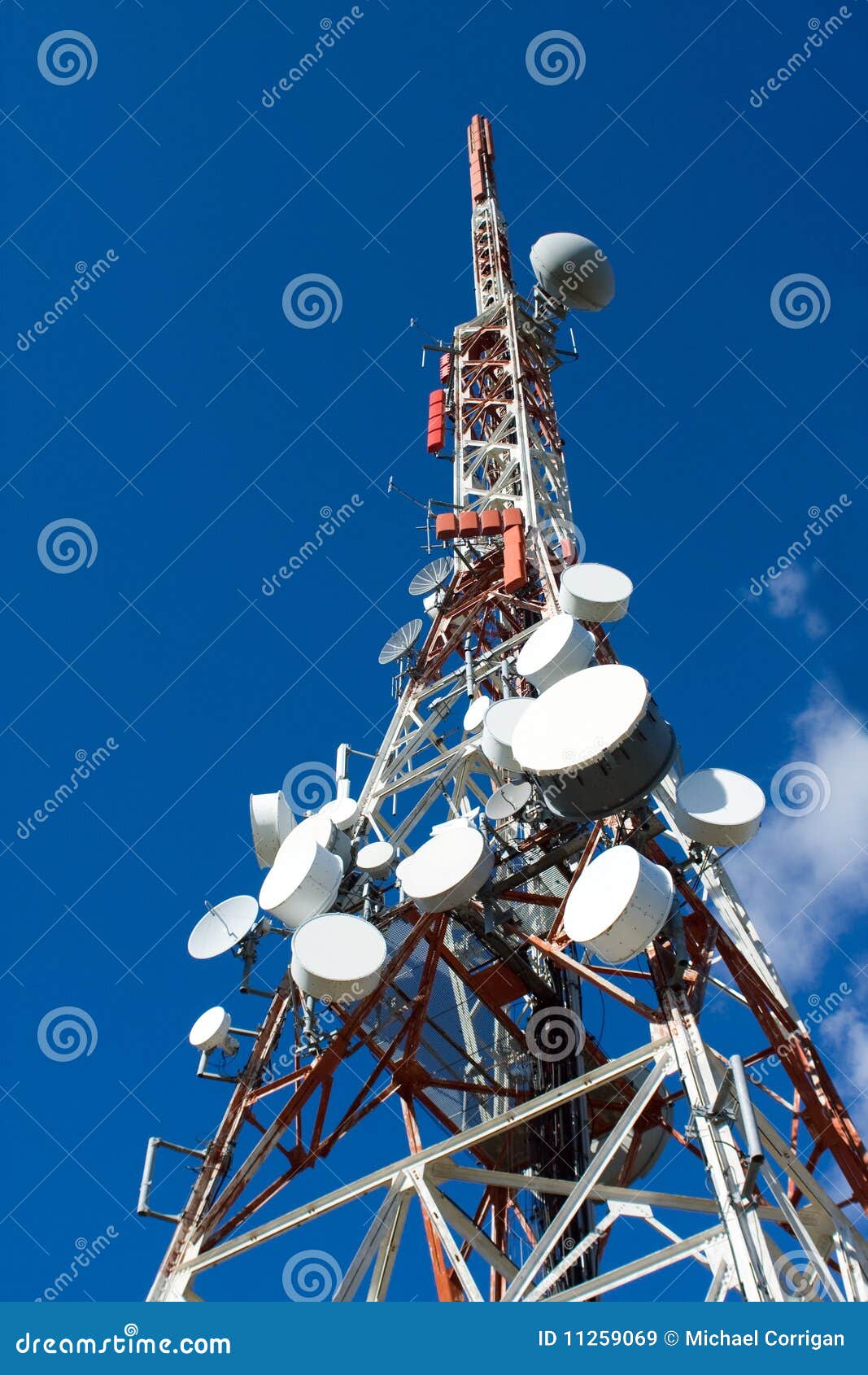 Cilindros da antena no mastro do telefone móvel. Mastros vermelhos do telefone móvel com as antenas brancas de encontro ao céu azul