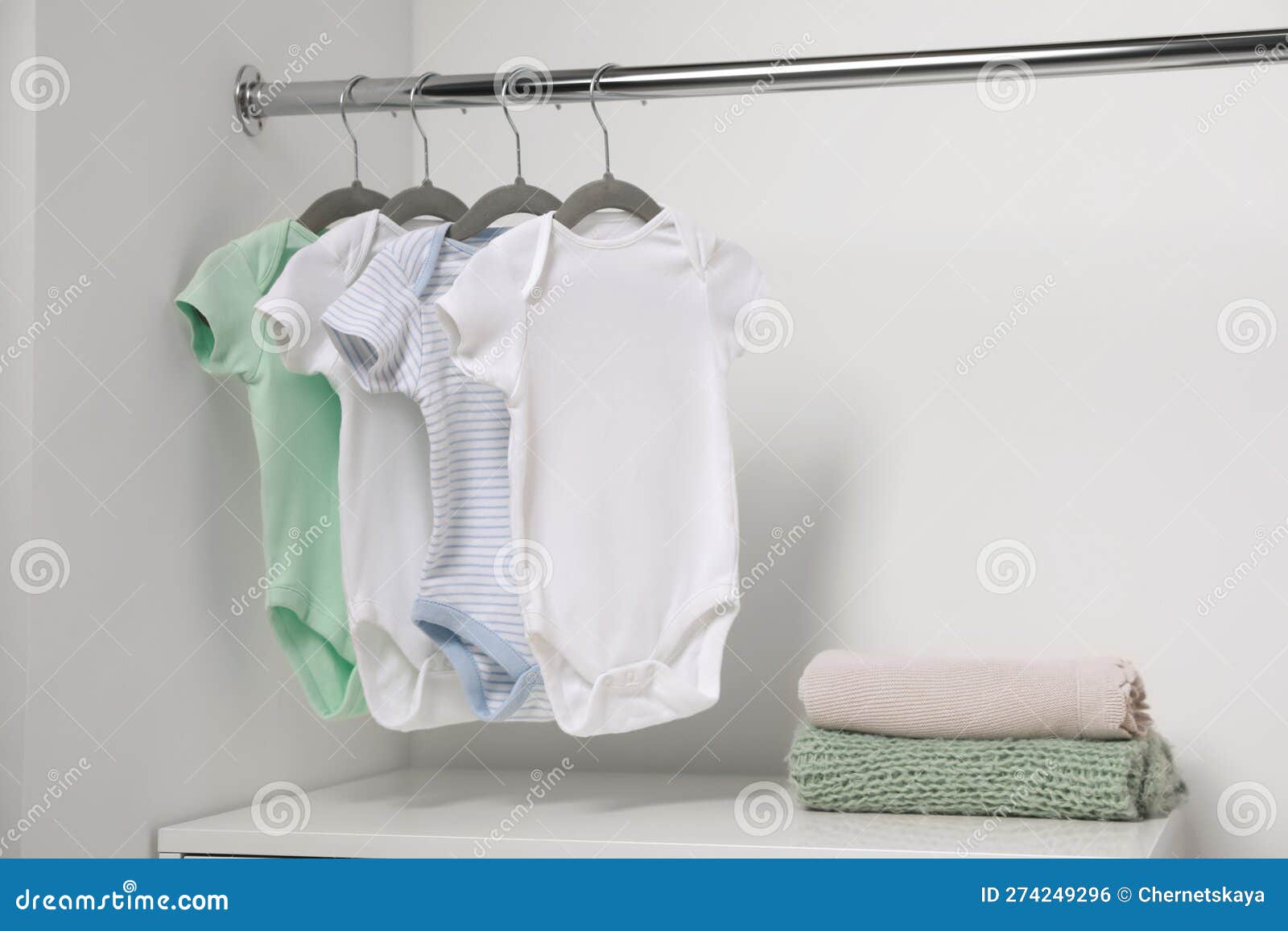 Cintres Avec Des Costumes Pour Bébé Et Des Piles De Vêtements Près Du Mur  Blanc. Espace Pour Le Texte Photo stock - Image du innocence, babyhood:  274249296