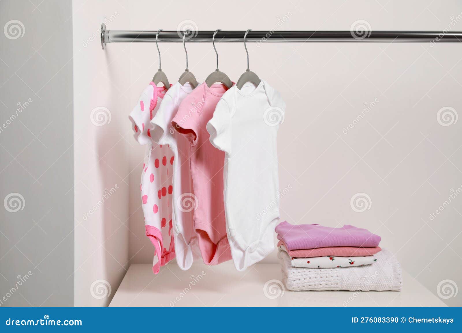 Cintres Avec Des Costumes Pour Bébé Et Des Piles De Vêtements Près Du Mur  Blanc Photo stock - Image du arrêter, combinaisons: 276083390