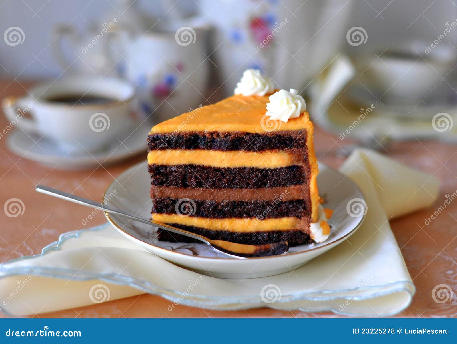 Cioccolato operato &amp; torta arancione. Il servizio elegante del cioccolato &amp; della fetta arancione della torta con il caffè della porcellana/articoli per la tavola del tè ha impostato nei precedenti