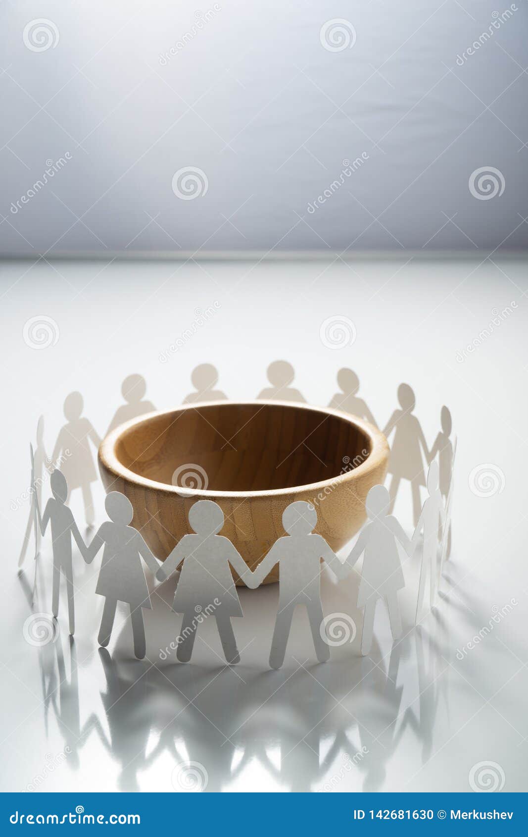 circle of paper people holding hands in front of big empty bowl. overpopulation, famine concept.