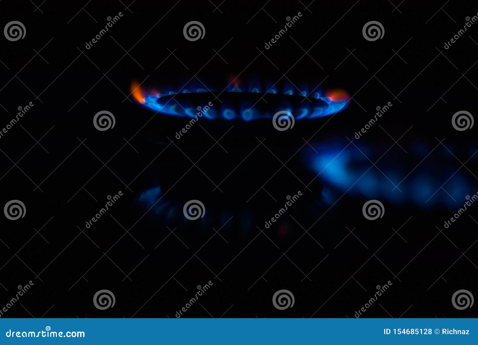 Circles of Fire on a Gas Stove in the Dark. Blue Flame Reflected on the