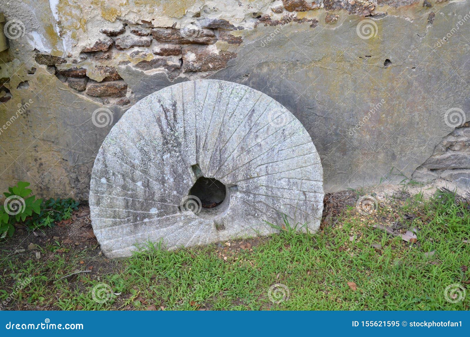 Circular Stone from Grinding Mill in Ground Near Old Brick Wall Stock