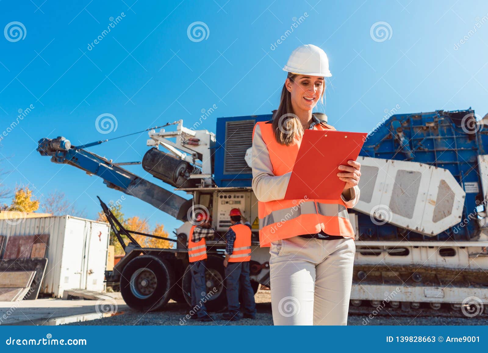 Civil Engineer Woman with Clipboard in Front of Stone Crusher Stock