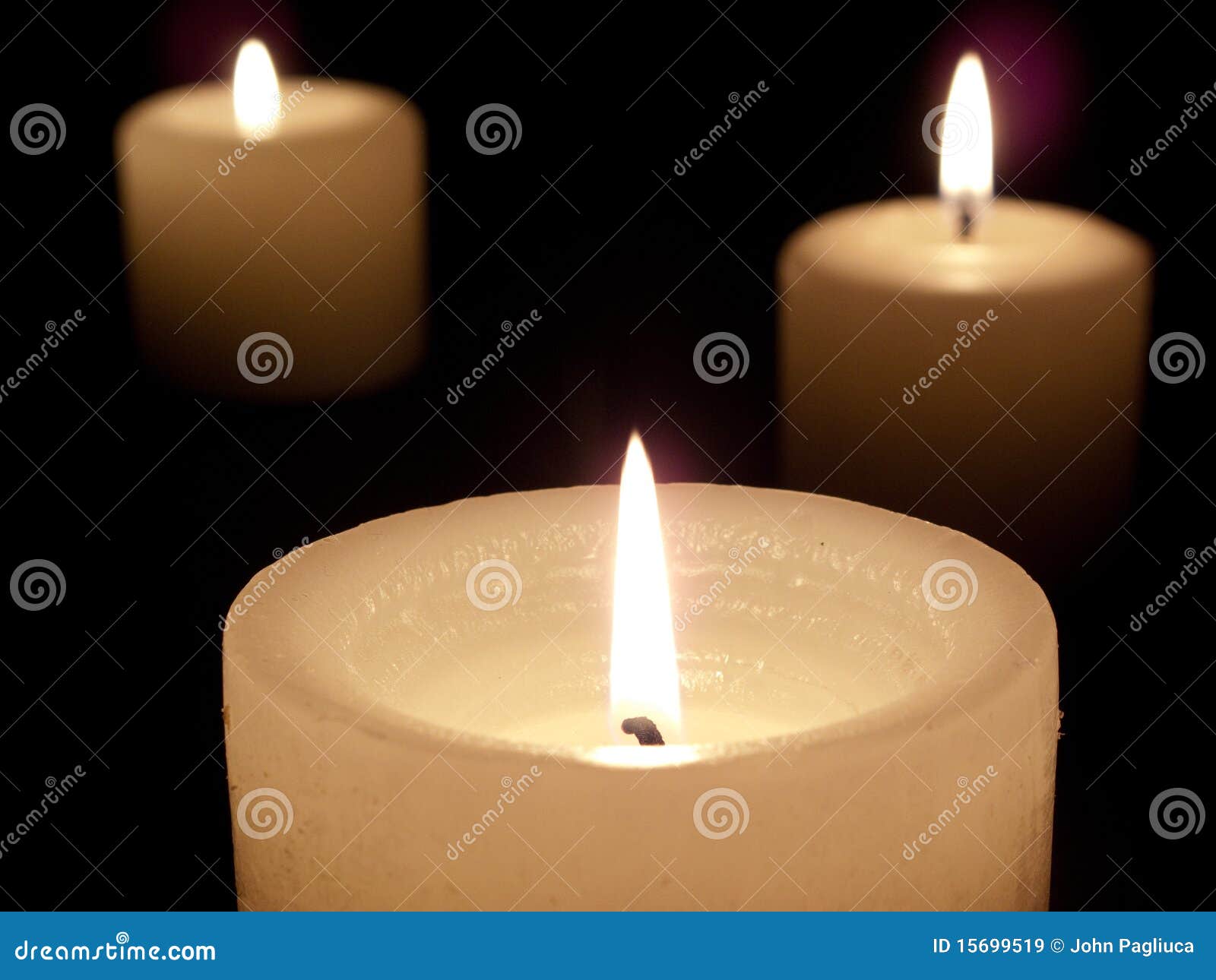 Ciérrese para arriba de tres velas encendidas en fondo negro. El cierre para arriba de tres encendió las velas blancas en fondo negro.