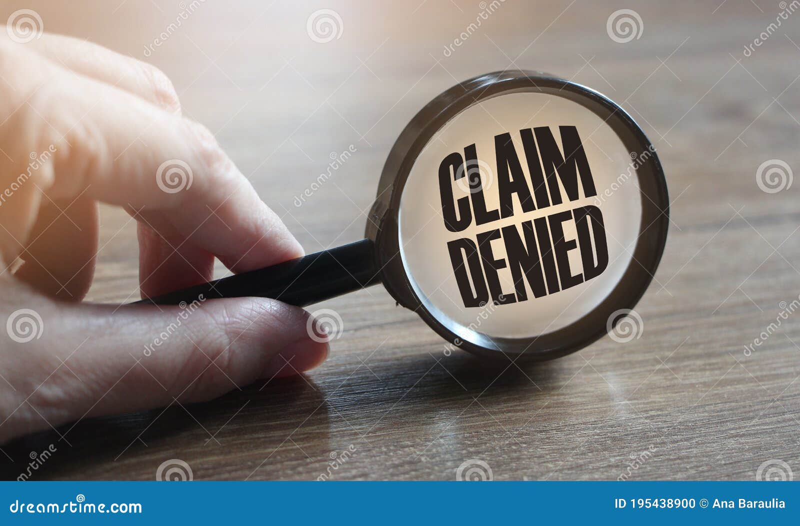 claim denied in a magnifying glass on a wooden table. insurance business concept