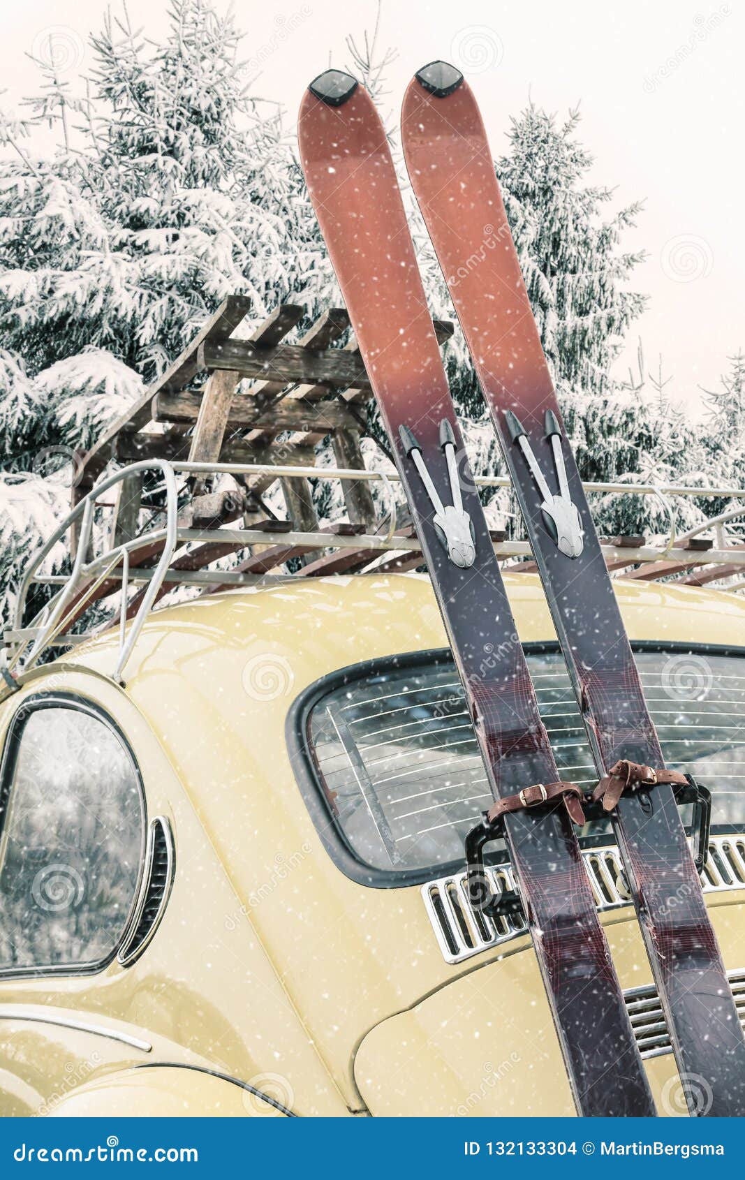 classic car with vintage ski`s and sled during snowfall