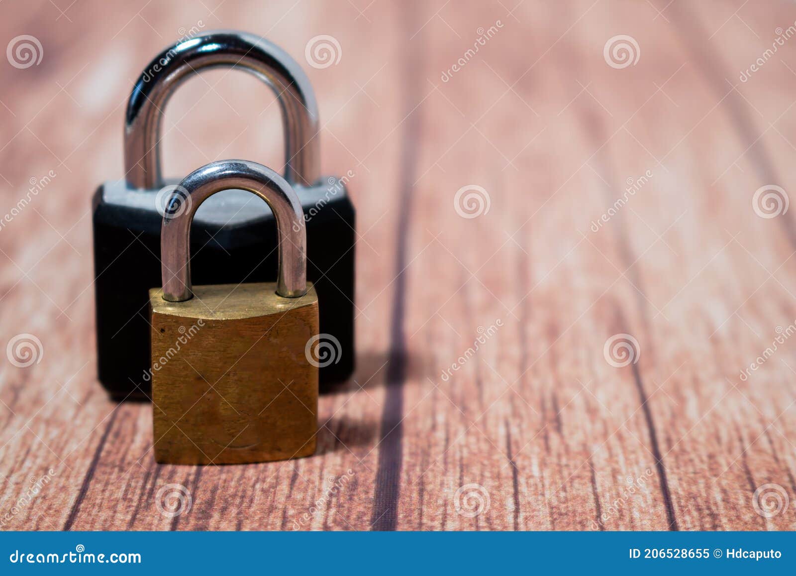 classic golden bronze padlock and black steel and iron padlock. space for writing. wooden background