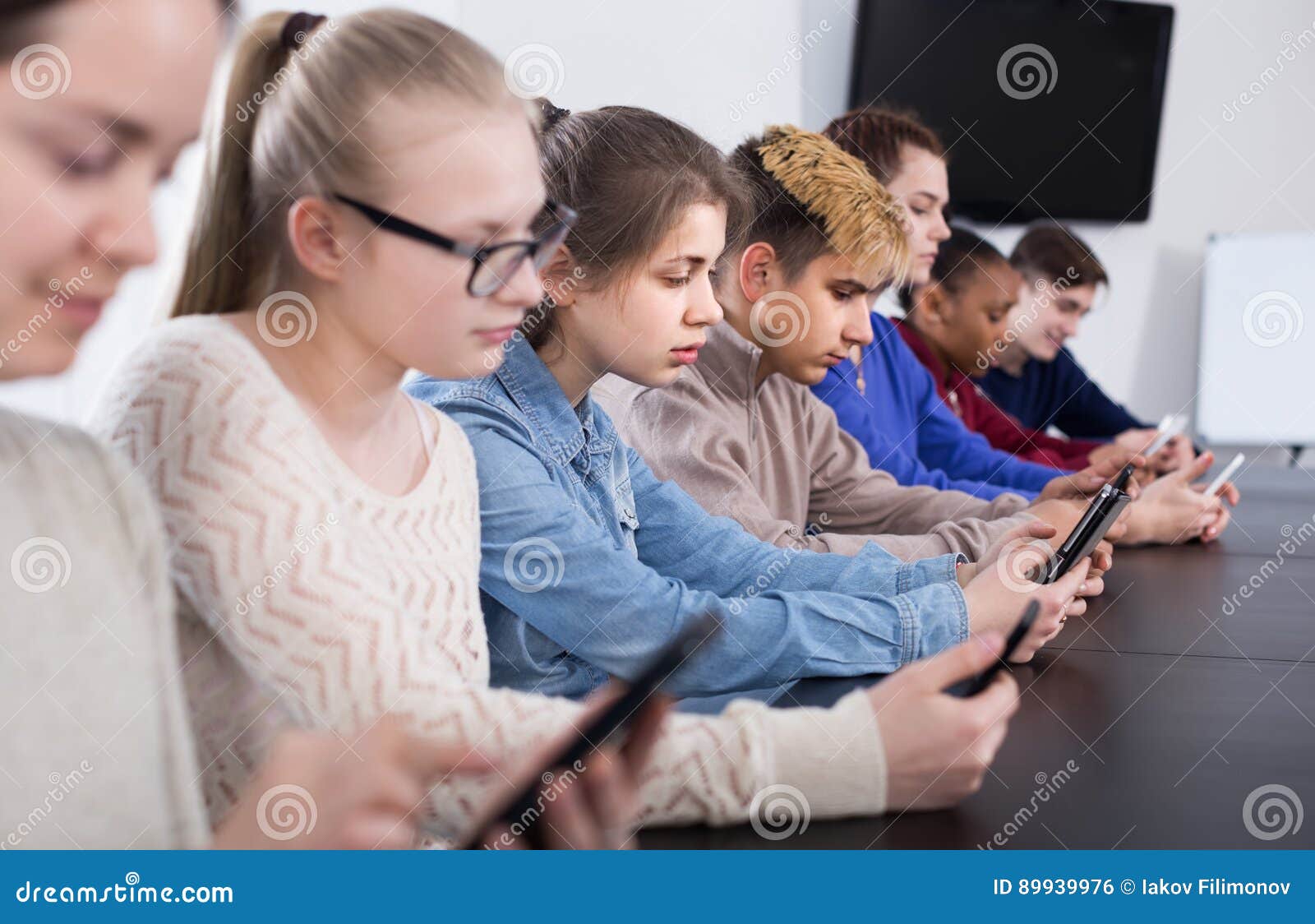 Classmates Using Their Smartphones Heavily during Classes Stock Photo
