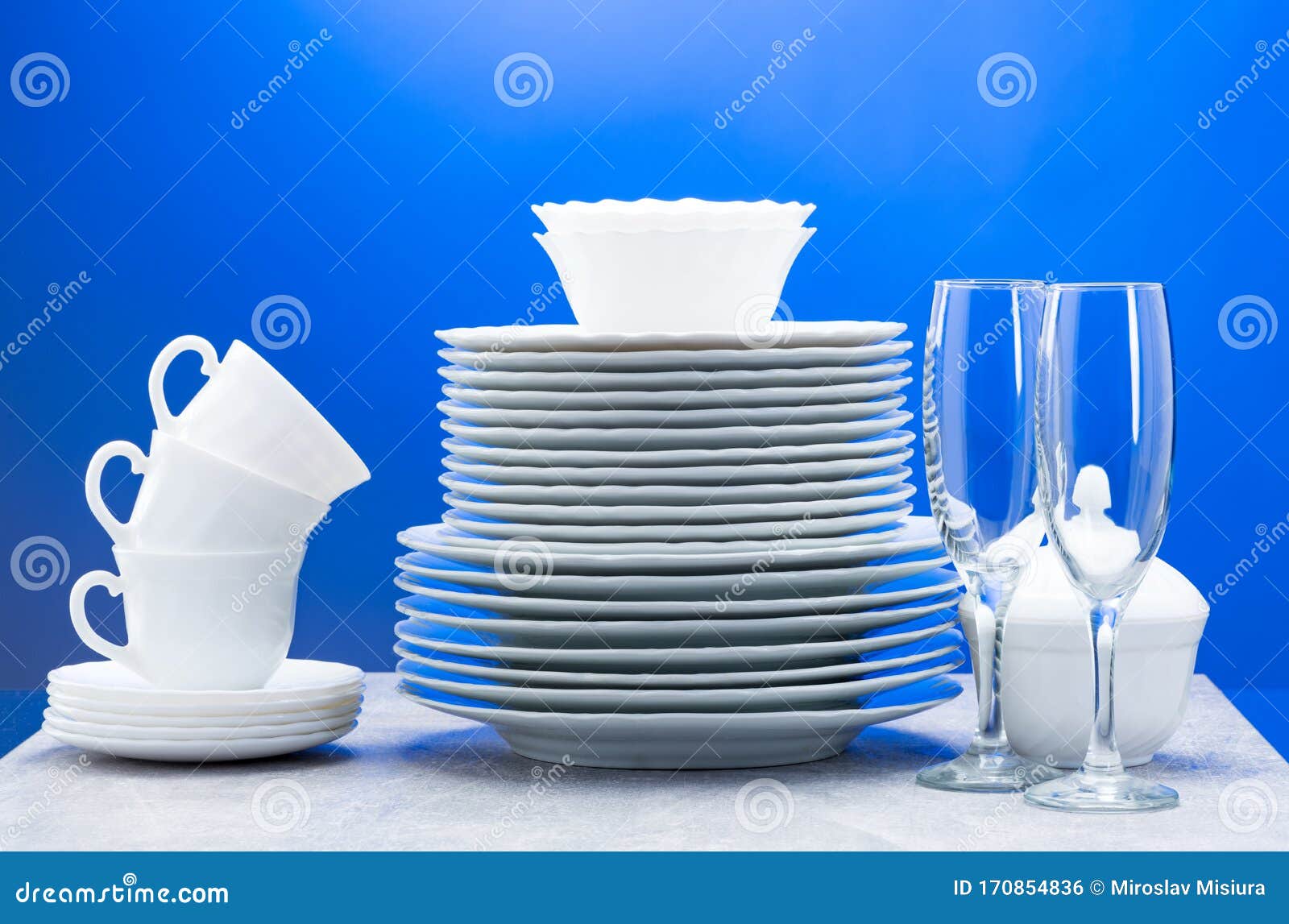 Clean Plates, Glasses, Cups and Cutlery on Blue Background Stock Photo