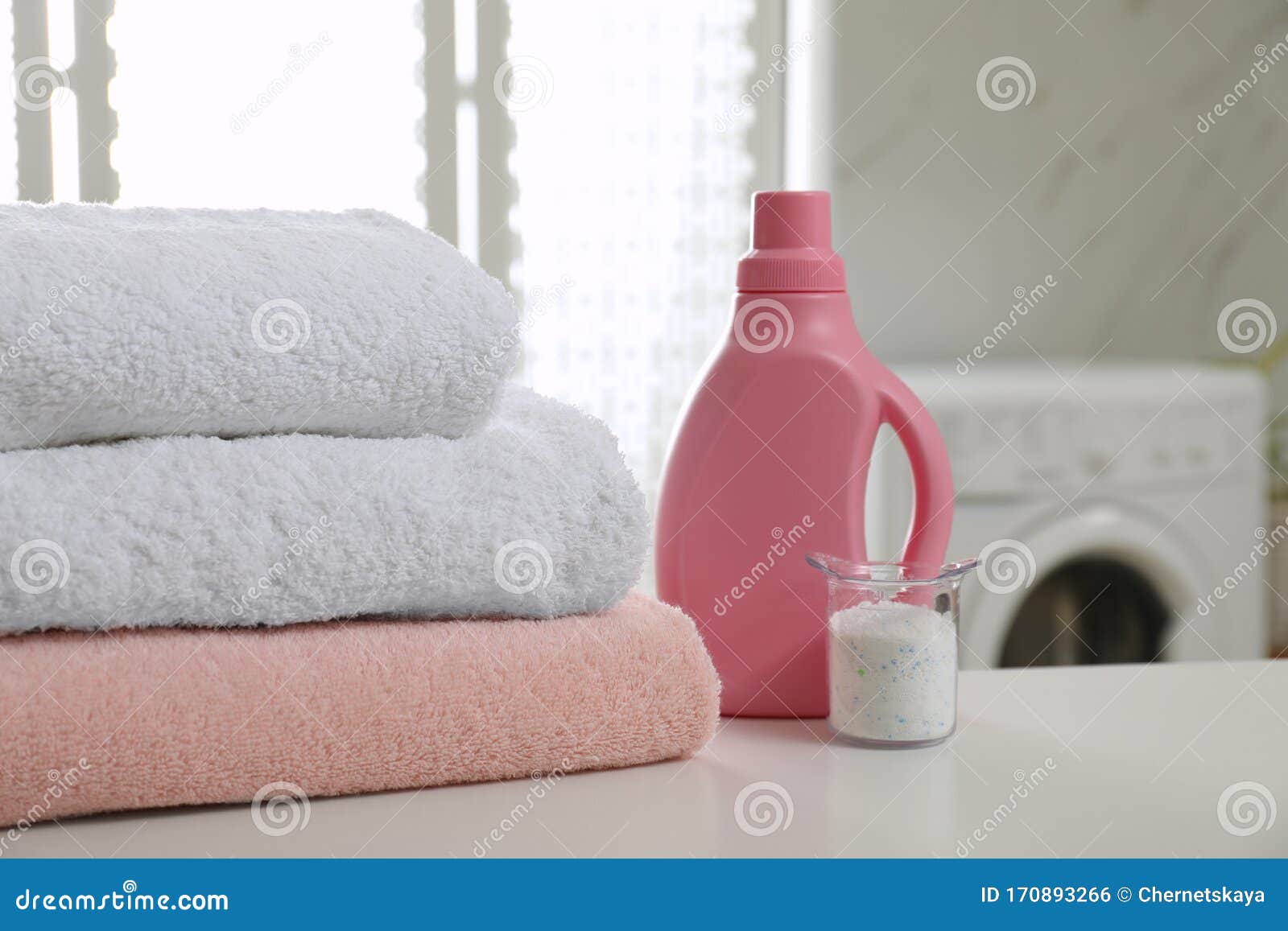 Clean Towels and Detergents on Table in Laundry Room Stock Photo