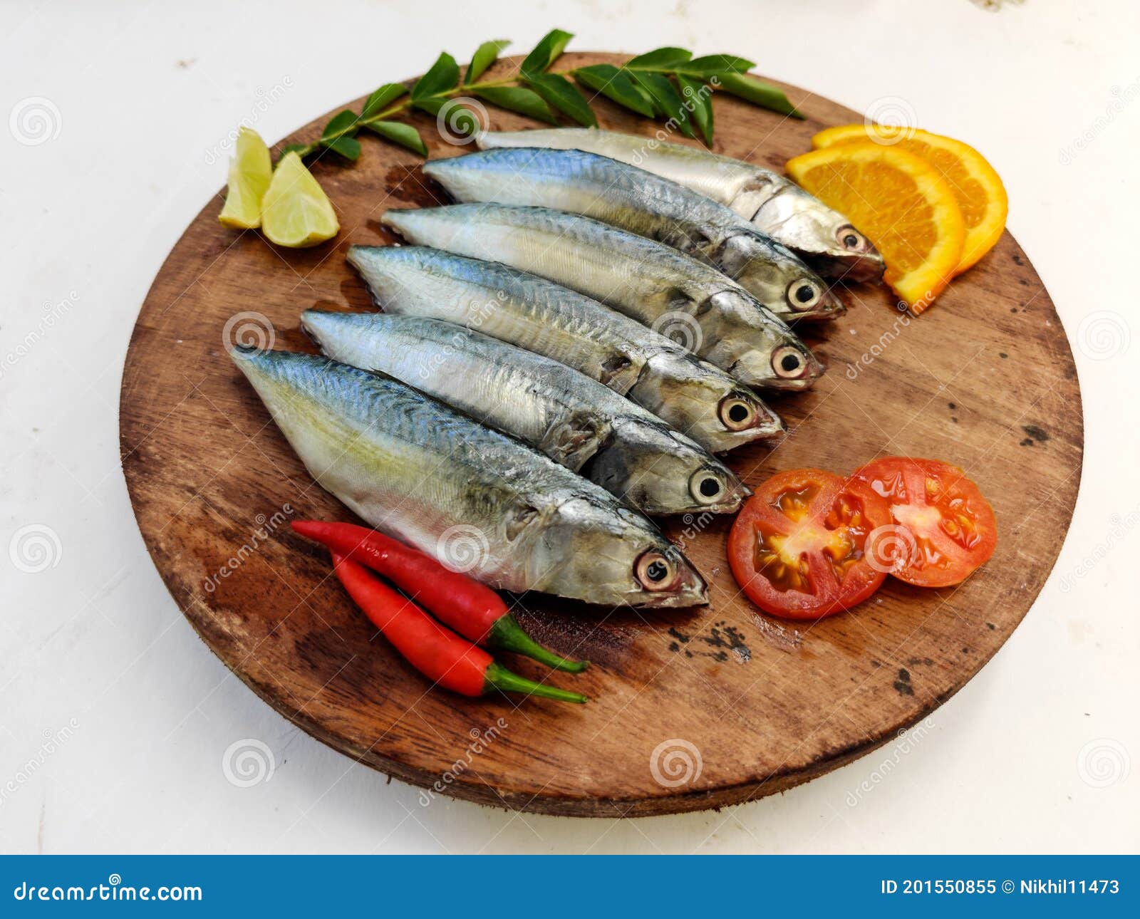 ready to cook fresh fish horse / indian mackerel fish decorated with herbs and vegetables on a wooden pad