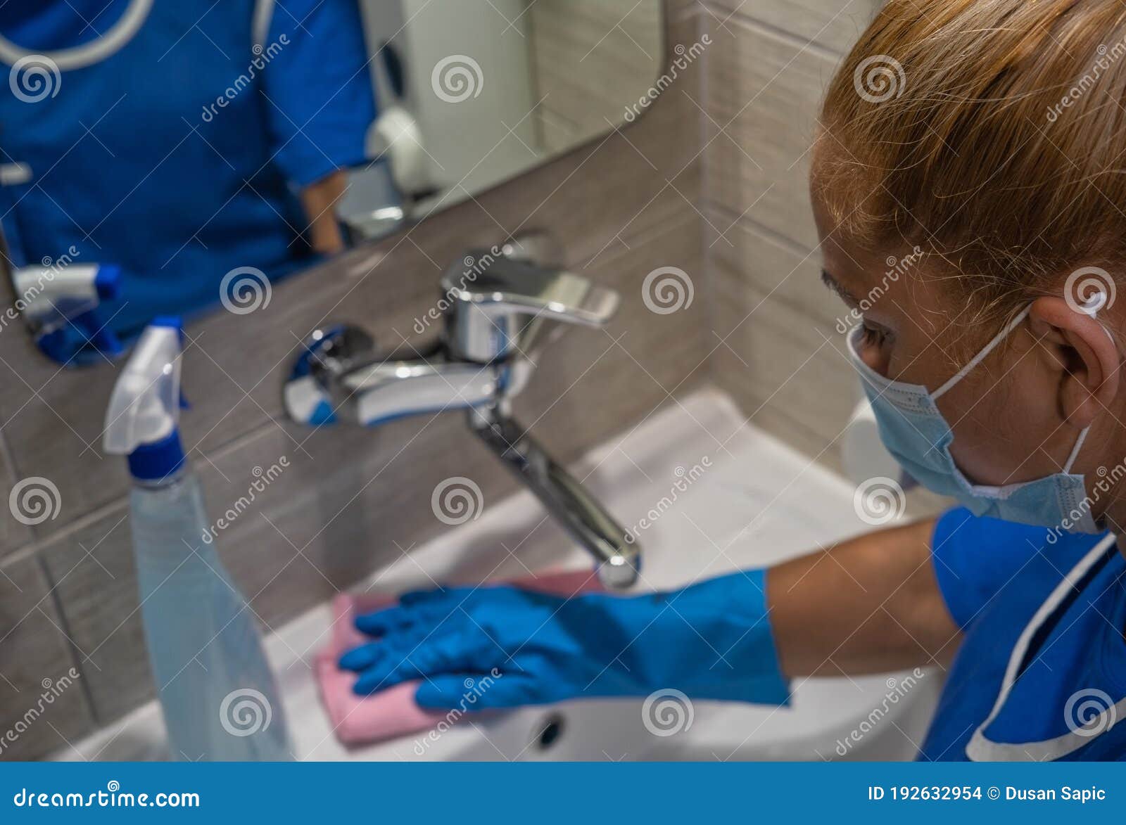 a cleaning leady with mask on her face cleans the washbasin