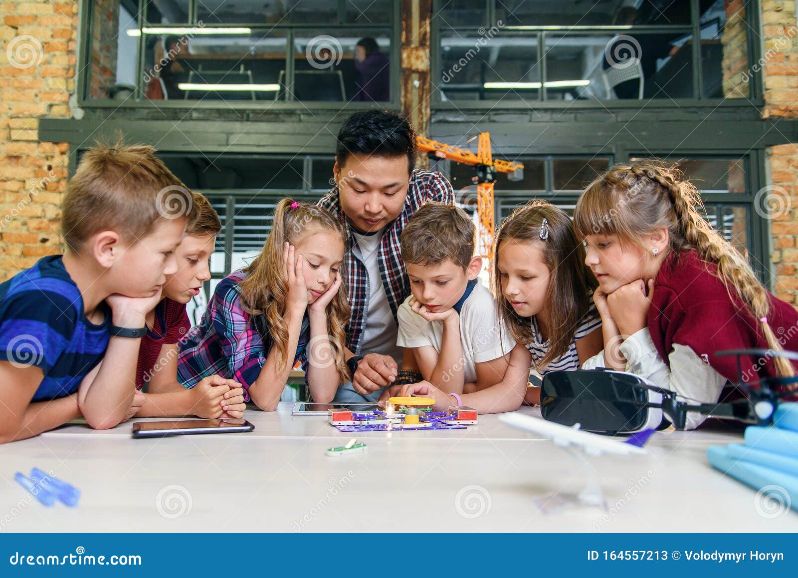 clever school children with asian male teacher investigate electronic constructor with turning fan and bulb. creative