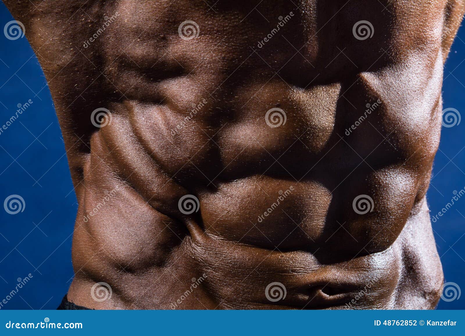 Closeup of Abdominal Muscles Bodybuilder on a Blue Background Stock