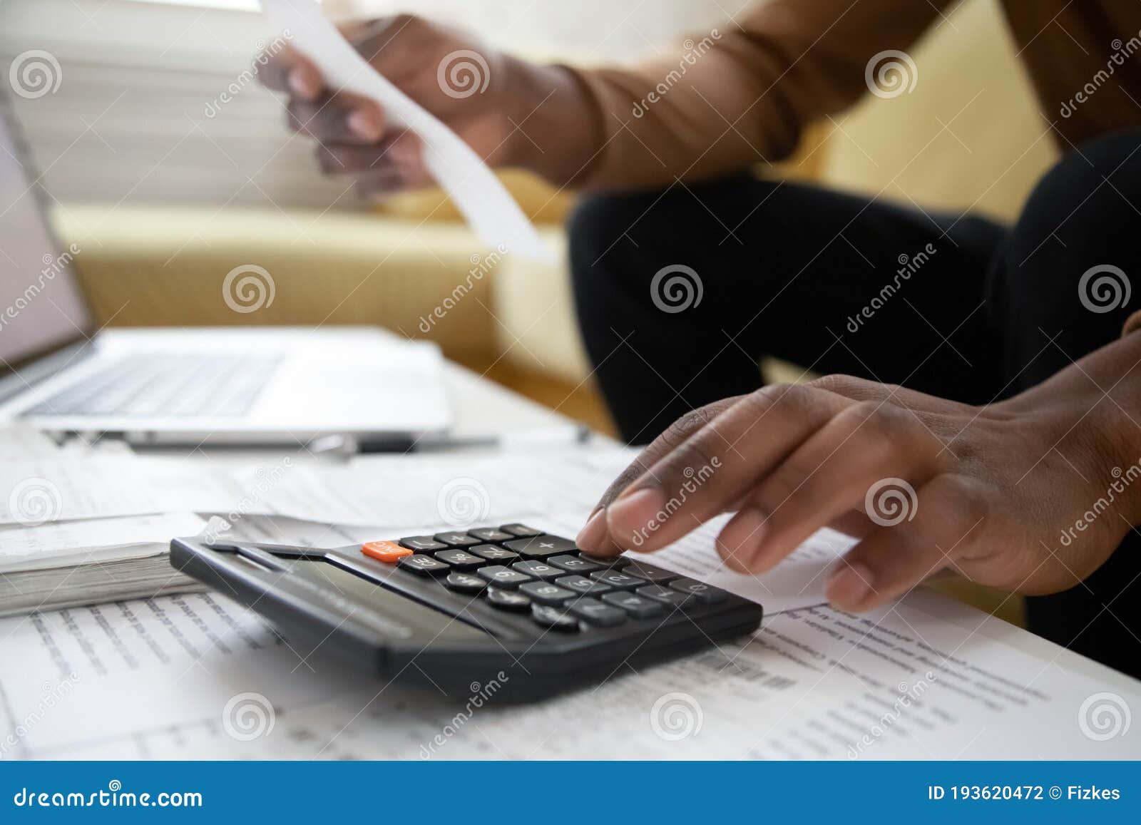 close up of african american man with calculator checking bills