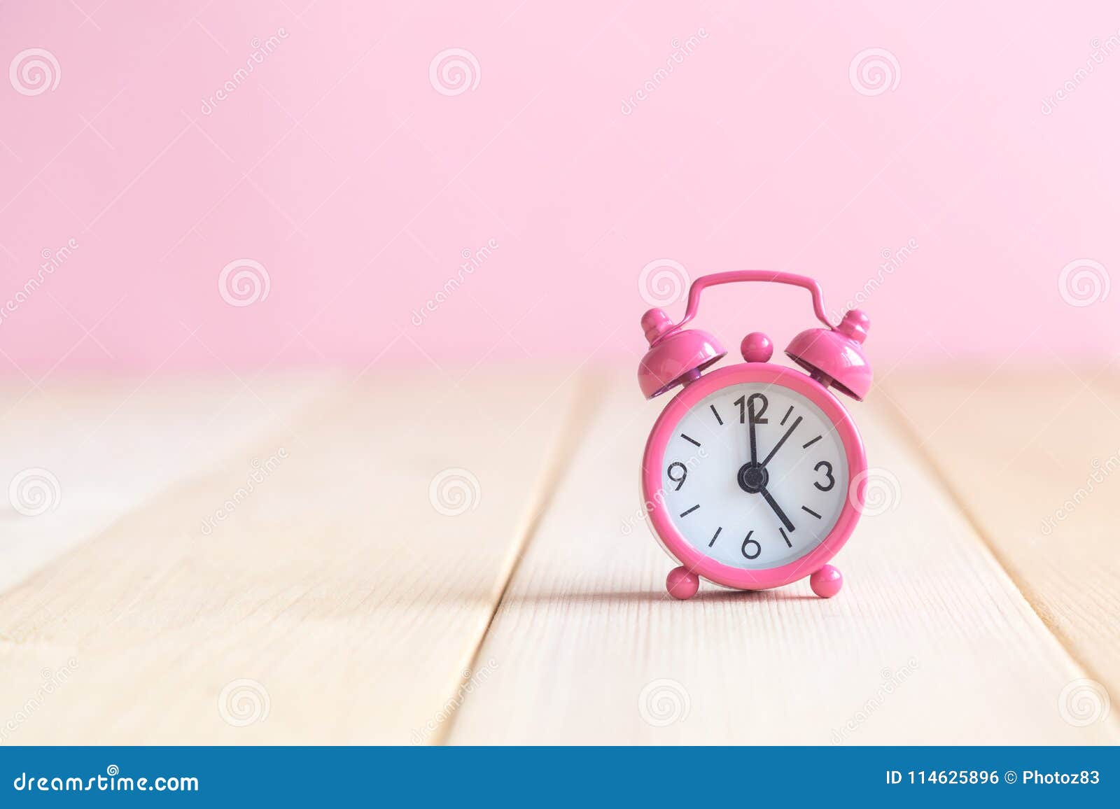 Close Up Of Alarm Clock On Desk Against Pastel Pink Background