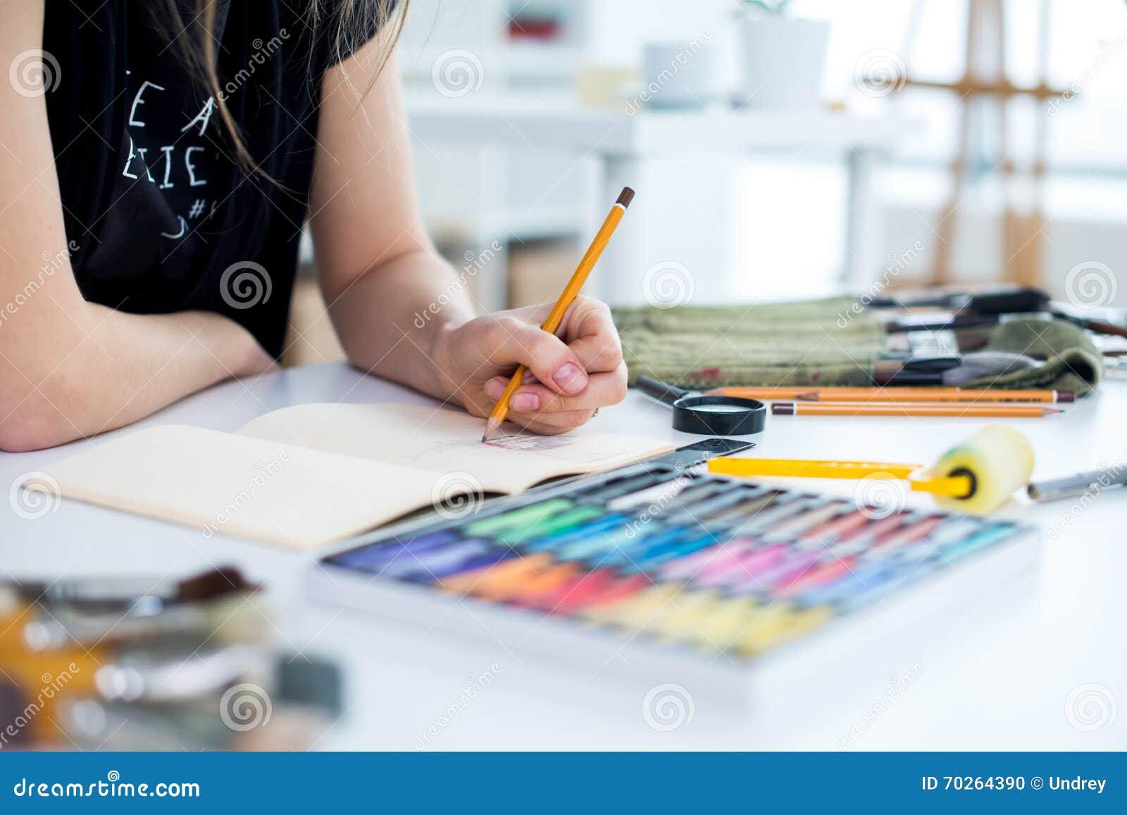 close-up angle view of a female painter drawing draft at sketchbook using pencil. artist sketching in art studio with