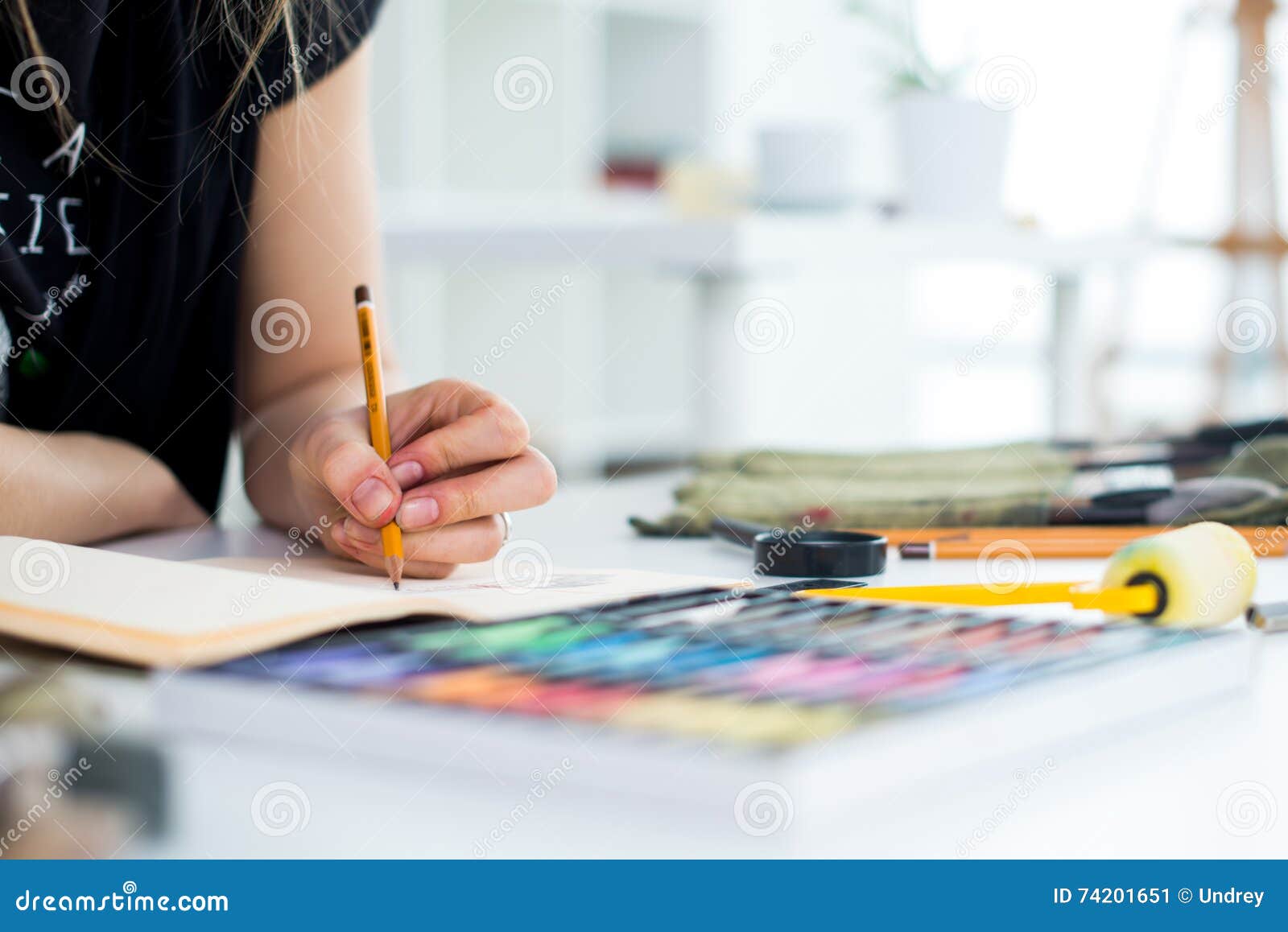 close-up angle view of a female painter drawing draft at sketchbook using pencil. artist sketching in art studio with