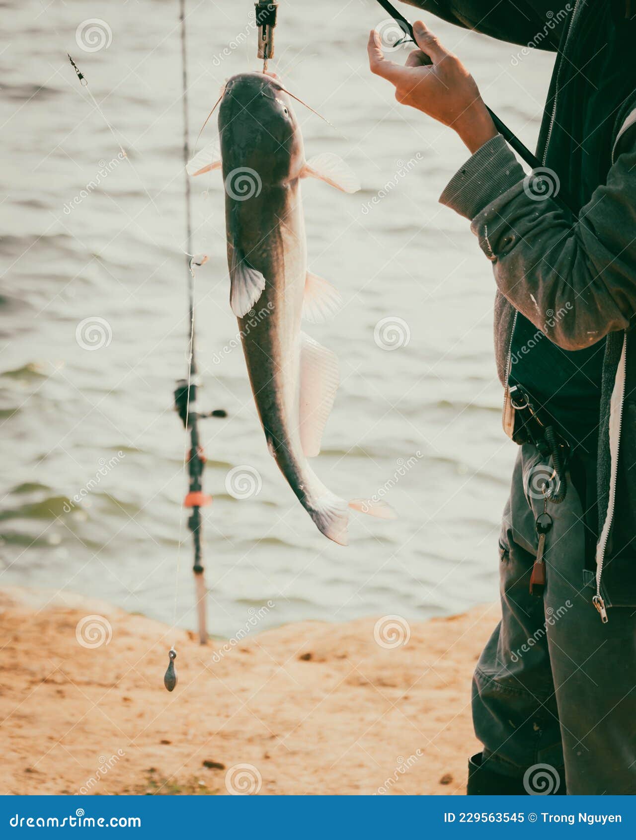 Close-up Asian Man Wear Fishing Boot with Rod and Fish Lip Gripper