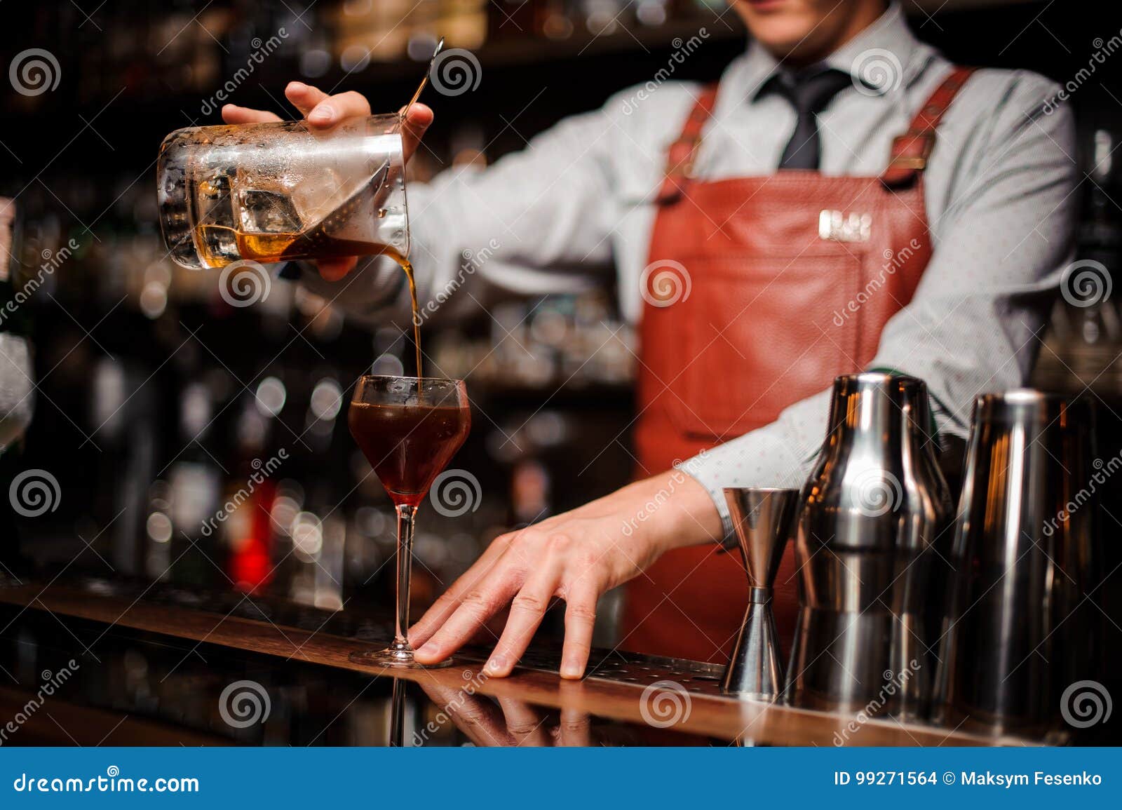 close up bartender pouring bright red alcohol cocktail into fancy glass