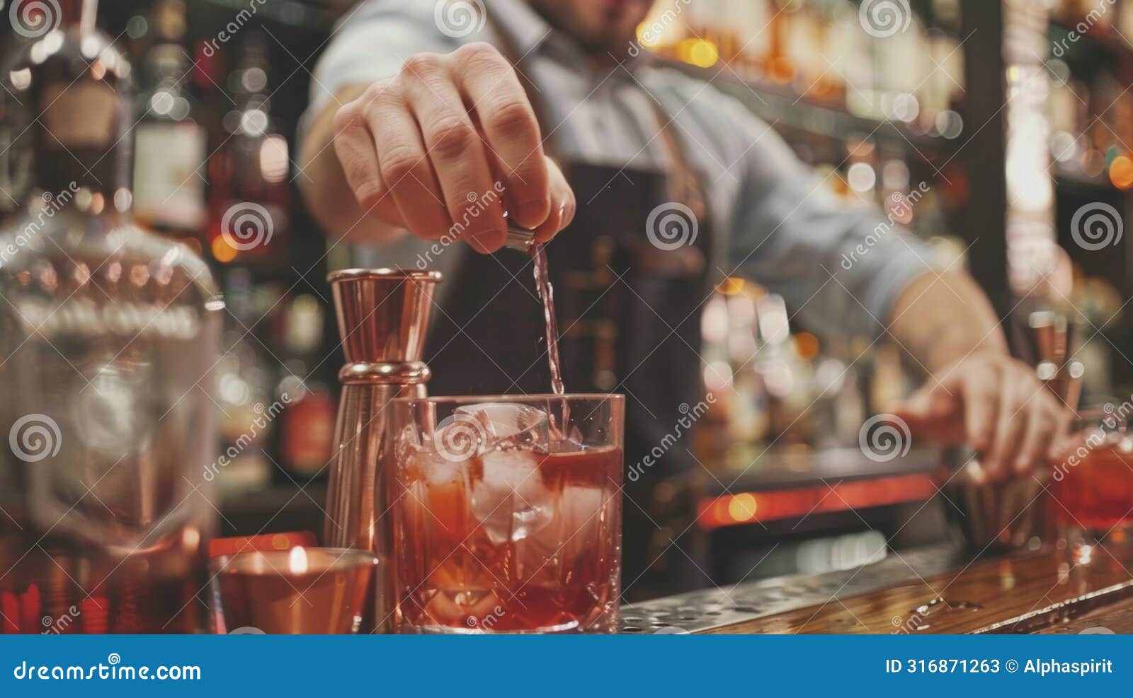 close-up of bartender pouring a drink into a glass with ice at a dimly lit bar
