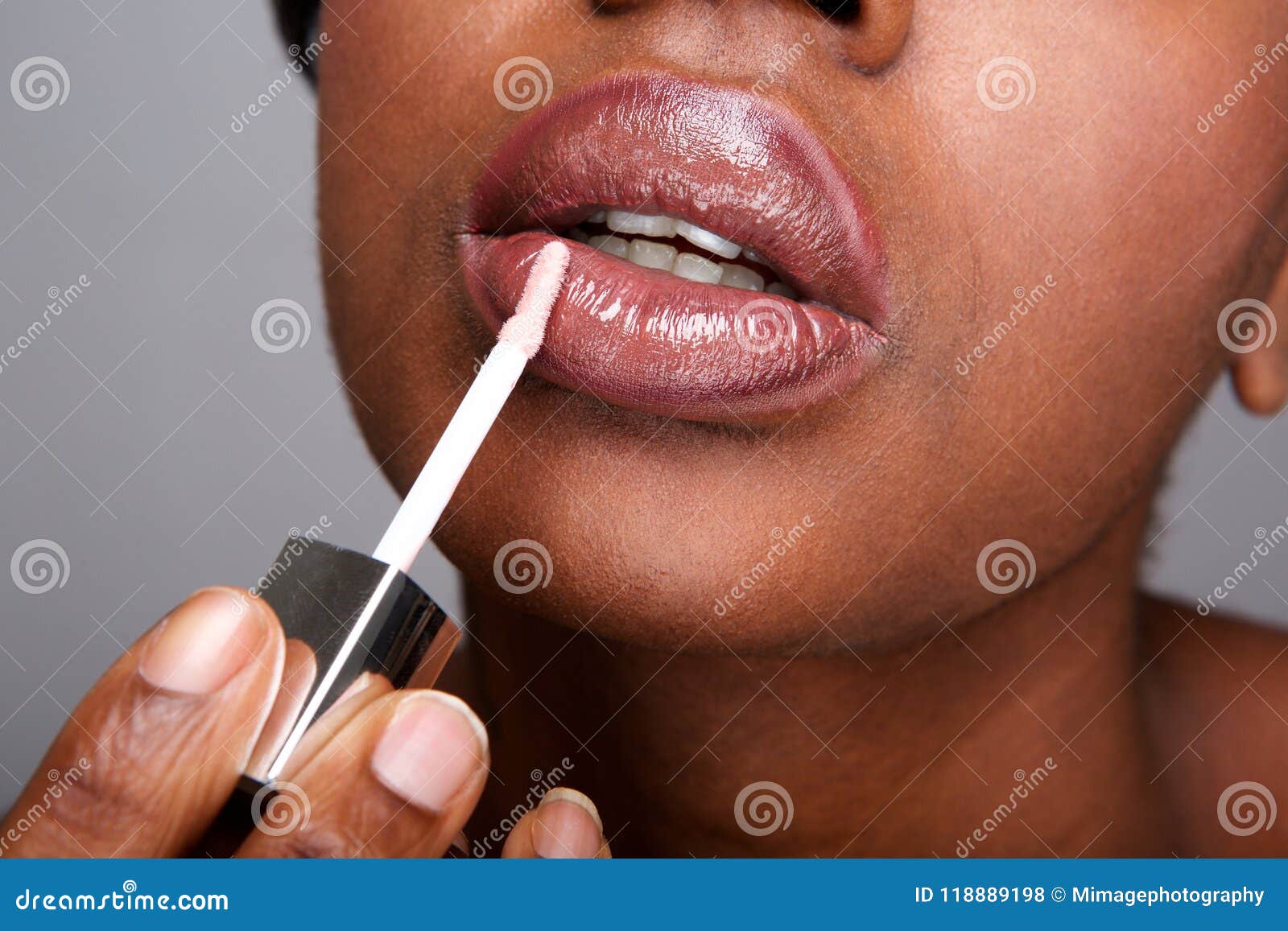 close up beautiful african american woman applying shiny lip gloss