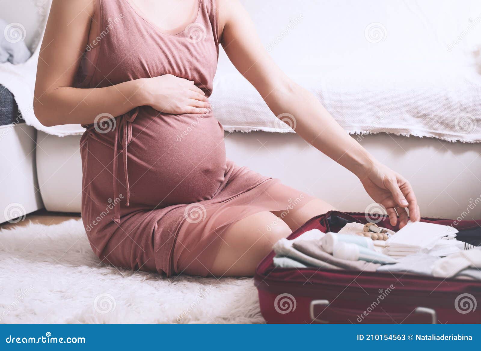 close-up belly of pregnant woman with travel bag of clothes and necessities. mother during pregnancy preparing and packing