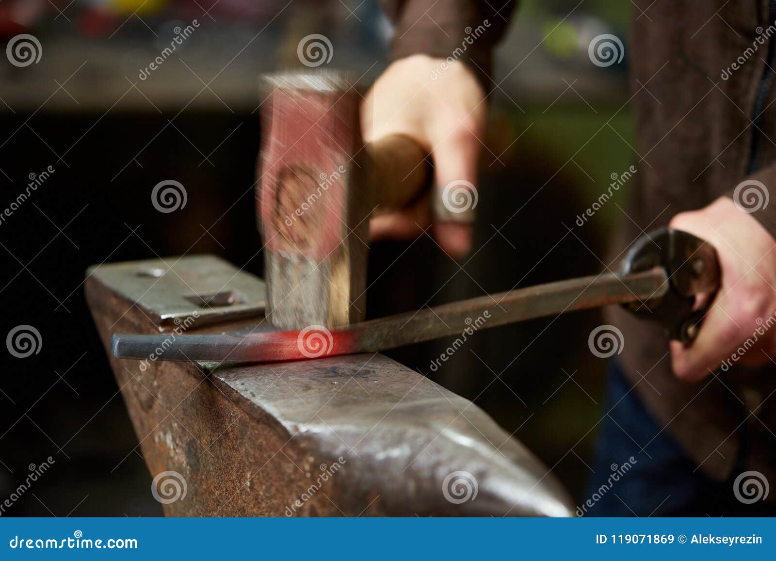 close-up of a blacksmith`s hands manipulating a metal piece above his forge, selective focus.